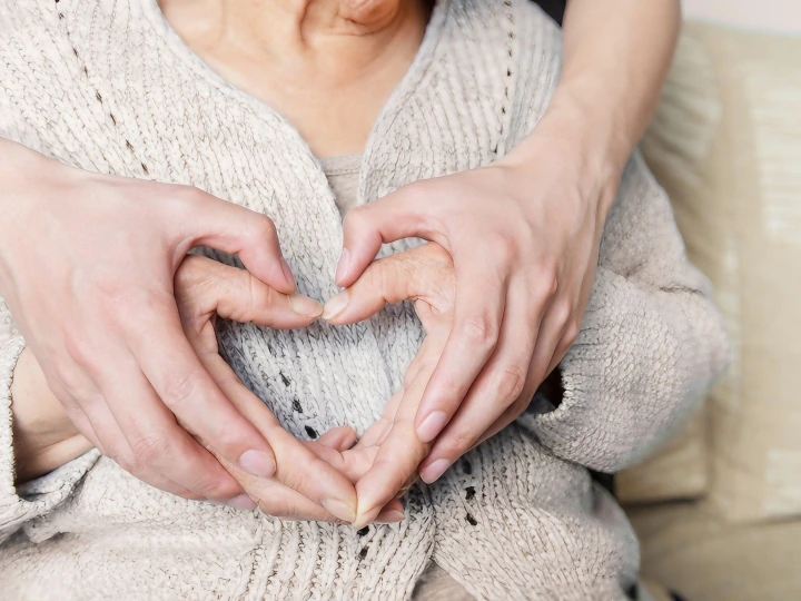 Chăm sóc người cao tuổi tại nhà TP.HCM — bàn tay người chăm chụm hình trái tim trên tay bà cụ