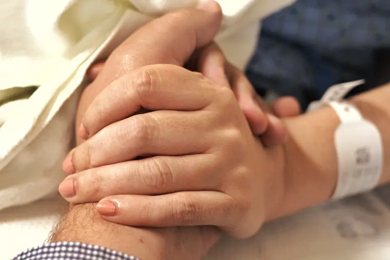 Dịch vụ nuôi bệnh TP.HCM — người nuôi bệnh nắm tay bệnh nhân nằm viện