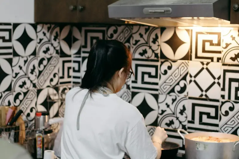 Giúp việc nấu ăn TP.HCM — người phụ nữ đứng nấu trong bếp gia đình ốp gạch bông, nồi canh lớn trên bếp